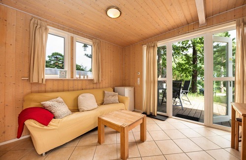 Gohren House | Achtern Dieck 68e Vacation Home in Baabe. A sunny terrace with its own beach chair and an idyllic view of the Baltic Sea through the trees. Comfortable living with underfloor heating