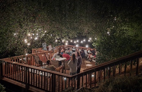 Redding House | Hillside home with large deck in a woodsy area.