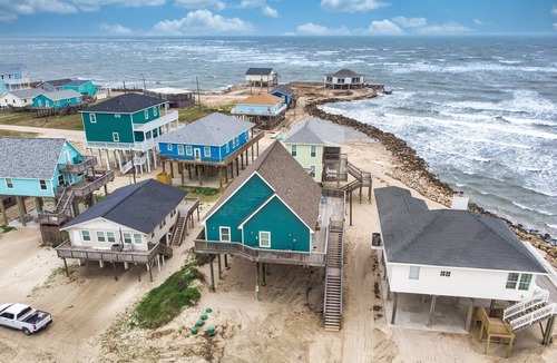 San Luis House | Martinis & Bikinis, a beach front house with toes in the sand drink in the hand.