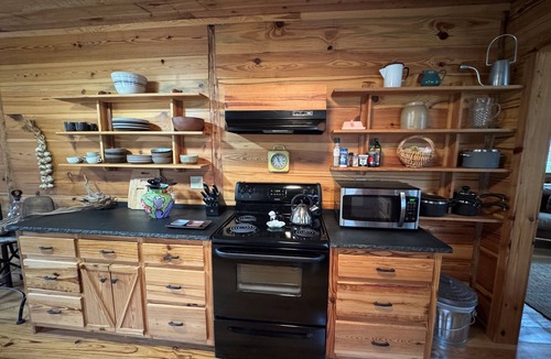 Ellijay Cabin | These charming cabins blend modern design with rustic beauty, offering a peaceful retreat where the main cabin sits one step from a stream, perfect for dining by the water, with stunning views of the surrounding landscape.
