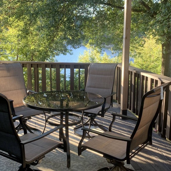 Lakeside house with fireplace, deck, and a fenced backyard with firepit.