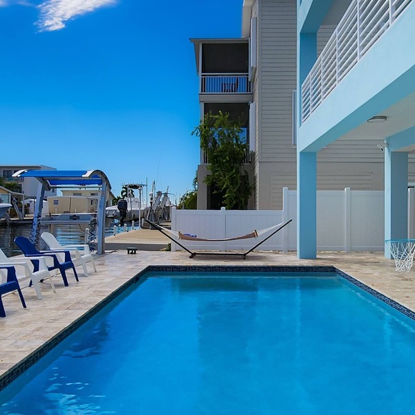 Sprawling waterfront home with pool, outdoor kitchen, game table, grill, & W/D