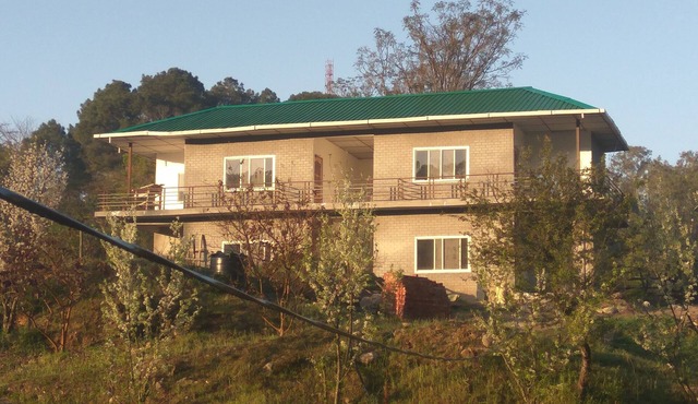 It is surrounded by lush green mountains, with fruit garden & vegetable fields.
