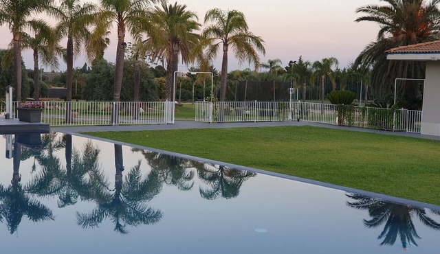 Orange house with large park and swimming pool.