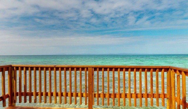 Rustic overwater cabin with oceanfront deck, island kitchen & sea breeze views